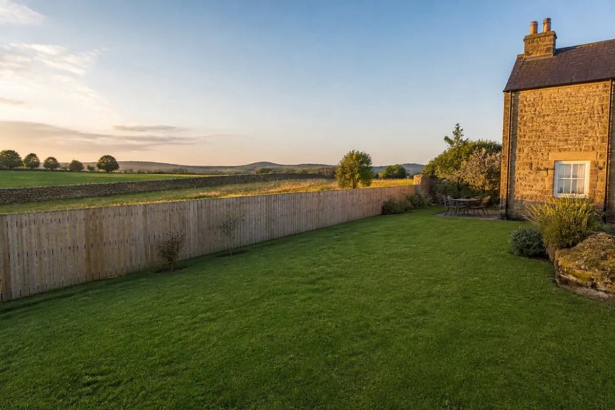 Closeboard fence along a large cottage garden with open fields beyond